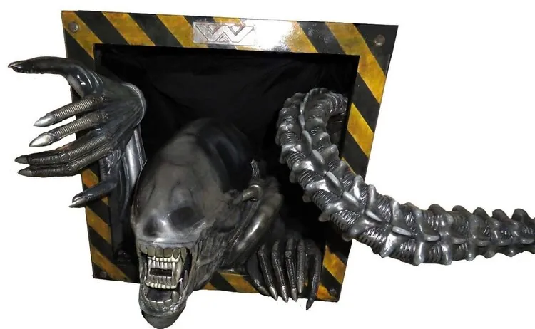 Finished Xenomorph display emerging through a hazard-striped frame
