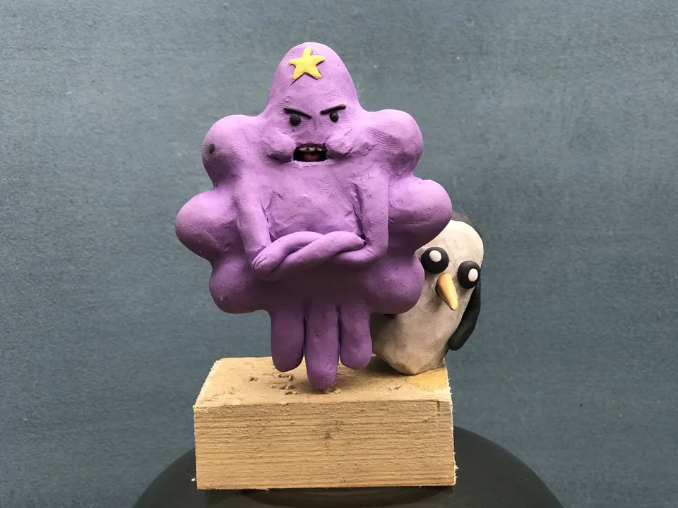 Purple plasticine character standing with folded arms