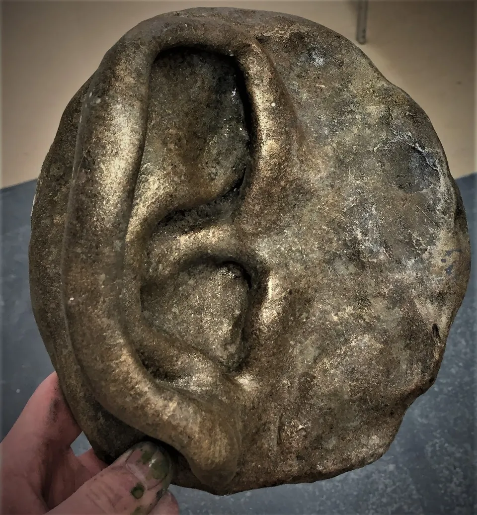 Sculpted ear relief on an oval backing