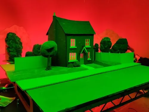 Miniature house and garden set under coloured lighting