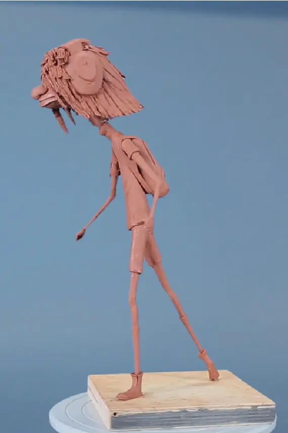 Full-length clay character sculpture on a wooden base